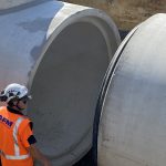 person looking at concrete holding tank pieces coming together